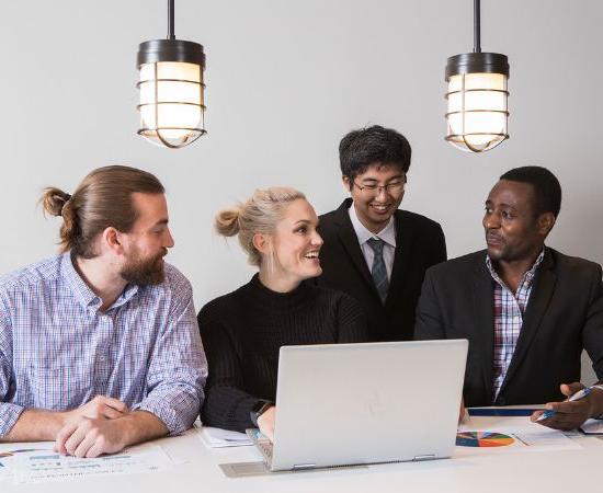 Four students in business attire working on a laptop